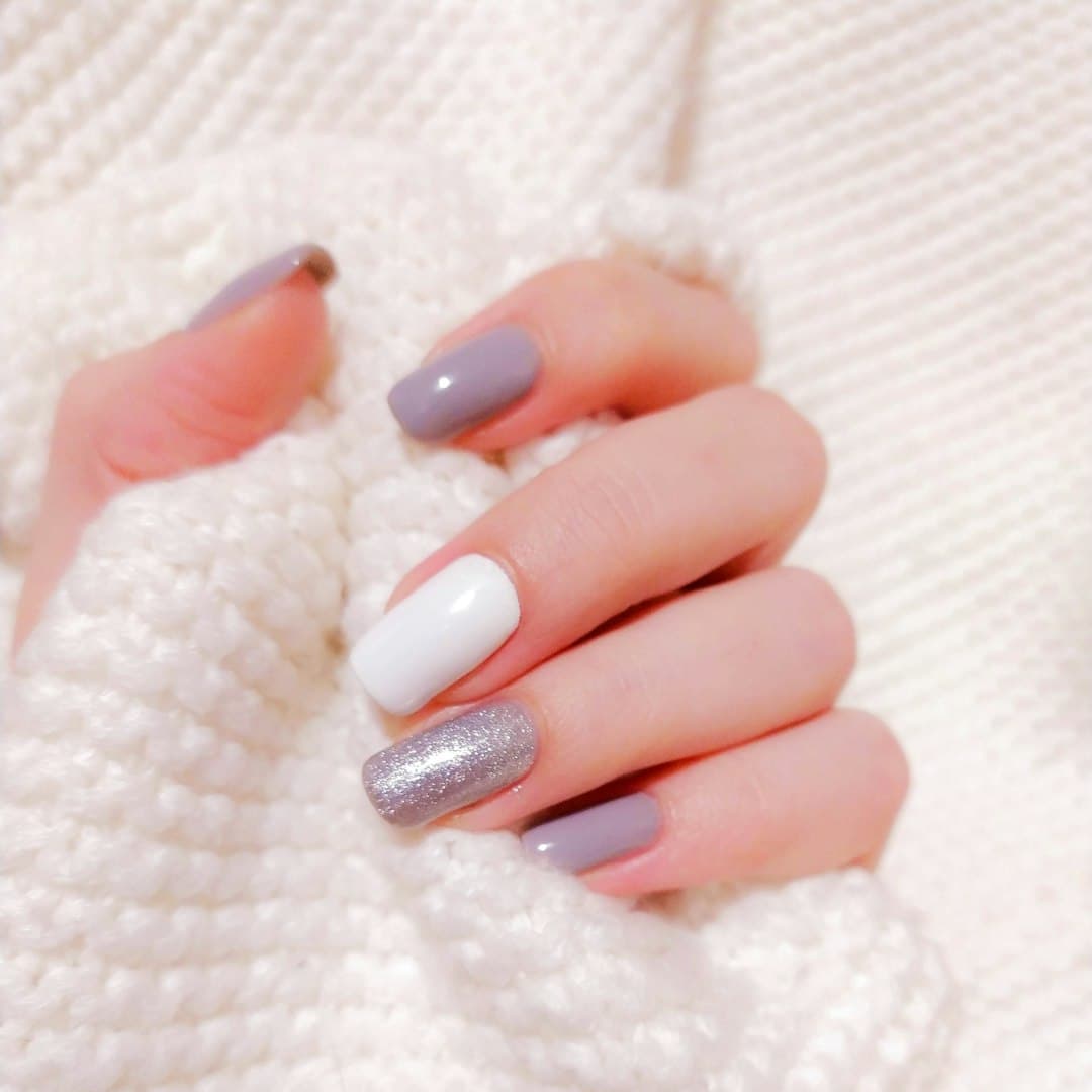 Glitter accent finger over a square set in grey and white.