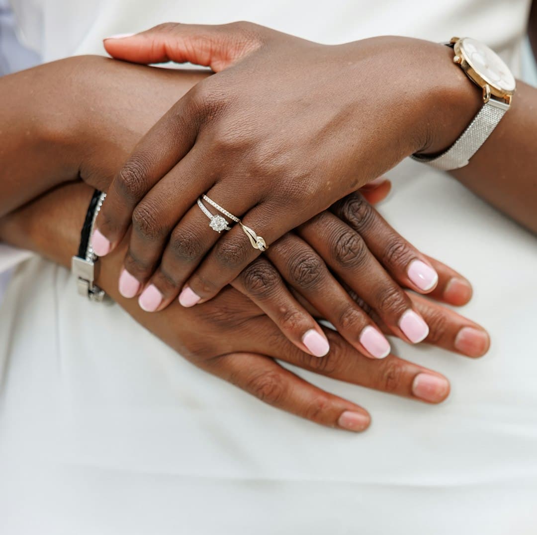 Soft pink manicure across two pairs of hands with diverse skin tones.